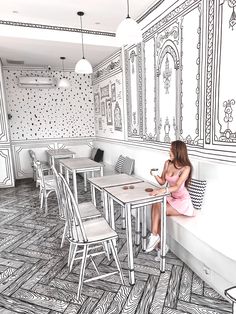 a woman sitting at a table in front of a wall with intricate designs on it