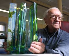 an older man is holding some green vases in his hand and looking at the camera