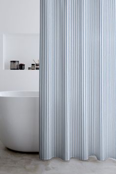 a white bath tub sitting next to a blue and white shower curtain in a bathroom