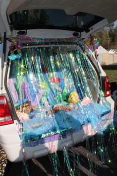 the back end of a white van with fairy land decorations on it's trunk