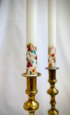 three candles with floral designs on them are standing next to each other in gold holders