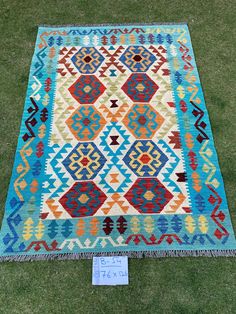 a multicolored rug on the grass with a price tag in front of it