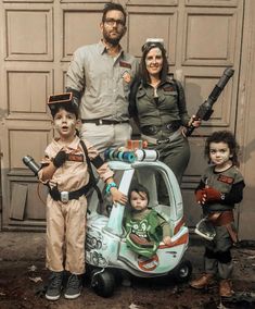 a family poses for a photo in front of an old garage door with their child's toy car