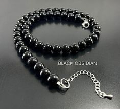 This Unique High Quality Black Obsidian (10mm, 8mm or 6mm)  Healing Crystal Beaded Necklace makes an Amazing gift they will ABSOLUTELY LOVE !  Crafted with High Quality Black Obsidian Crystal Beads , High Quality Beading Wire, Lobster Clasp & Adjustable Extender Please Note: The Necklace Length does not include the Extender (Extender is 1.5 inches) Perfect for Valentine's Day Gift , Birthday Gift , Anniversary Gift ,  Graduation Gift, Christmas Gift, Mothers Day Gift  , Fathers DayGift  , Gift f Obsidian Necklace And Earring, Envelope Necklace, Black Obsidian Crystal, Black Obsidian Bracelet, Obsidian Jewelry, Crystal Beaded Necklace, Pyrite Bracelet, Handmade Crystal Necklace, Energy Protection