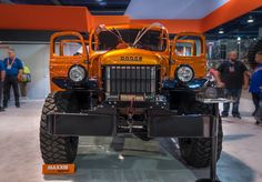 an orange truck is on display in a showroom while people look at it and talk