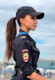 a female police officer in uniform is posing for the camera with her ponytail tied back