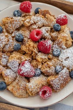 blueberries, raspberries and powdered sugar on top of a white plate