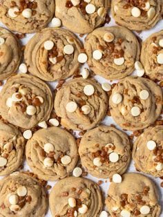 several cookies with white chocolate chips and nuts are arranged on a sheet of parchment paper