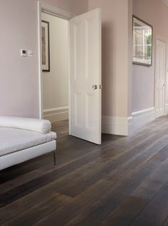 a living room with hard wood floors and white furniture on the floor, along with pink walls