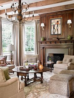 a living room filled with furniture and a fire place under a chandelier in front of a window