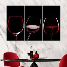 three wine glasses on a marble table with red wine in the middle and one empty