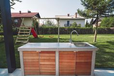 an outdoor kitchen with sink and swings in the back yard