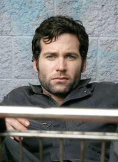 a man sitting in front of a cage with his hand on his chest and looking at the camera