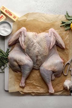 a raw chicken on a piece of paper next to garlic and other ingredients