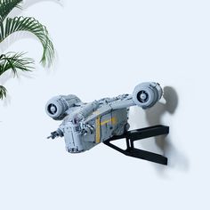 a lego star wars vehicle is hanging on the wall next to a potted plant