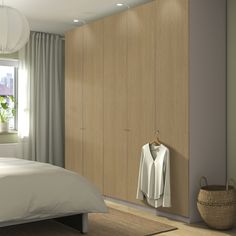 a bedroom scene with focus on the bed and clothes hanging on the closet doors,