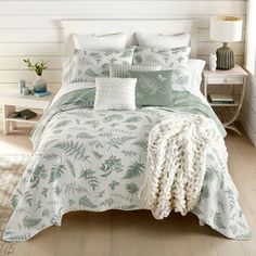 a bed with green and white comforters in a bedroom