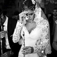 a woman in a wedding dress and veil holding a candle next to a man in a tuxedo