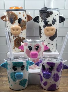 four different colored cow cups sitting on top of a table