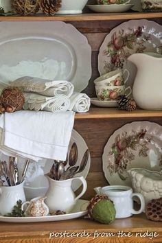 plates and dishes are stacked on top of each other with pine cones in the background