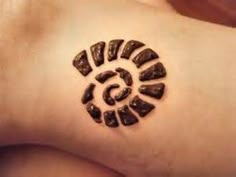 a person with a small tattoo on their left arm that has an image of a spiral in the middle