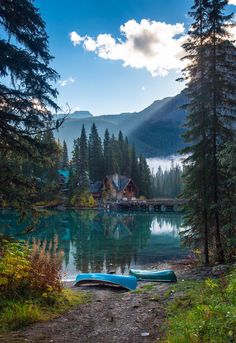 two canoes are sitting on the shore of a lake in front of a cabin