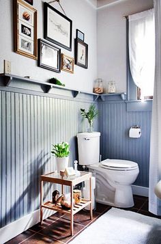 a white toilet sitting in a bathroom next to a wooden shelf with pictures on it