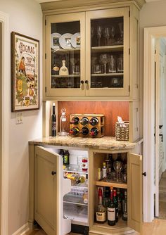 an open refrigerator in a kitchen next to a counter with wine bottles and glasses on it