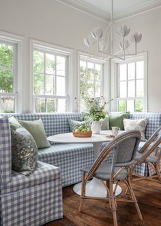 a blue and white checkered couch sitting in front of a table with flowers on it