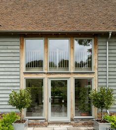 an outside view of a house with large windows and potted plants on the patio