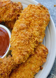 two fried chicken sticks on a plate with ketchup