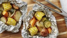 two tin foil wrapped potatoes and corn on the cob