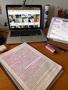 a laptop computer sitting on top of a wooden desk next to a notebook and pen