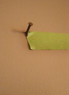 a green piece of paper with a screw stuck to it