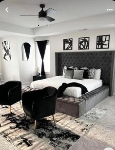 black and white bedroom with large bed, two chairs, rugs and pictures on the wall