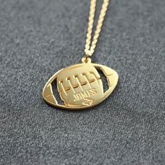 a gold football necklace with the name james on it