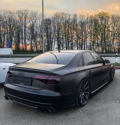 an audi car parked in a parking lot with trees in the back ground and sunset behind it