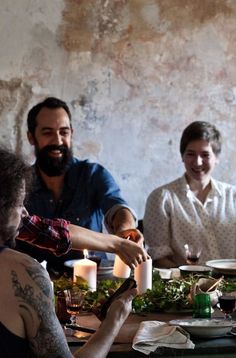 a group of people sitting around a table with plates and candles in front of them