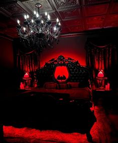 a bedroom with red lighting and chandelier above the bed in front of it