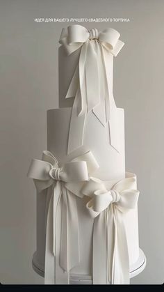 a three tiered white wedding cake with bows