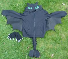 a bat costume laying on the grass with its wings spread out and eyes painted green