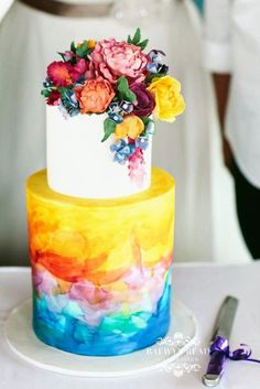 a multi - colored wedding cake with flowers on top