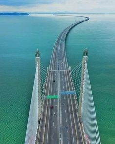 an aerial view of a bridge spanning the ocean with cars driving on one side and two lanes to the other