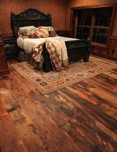 a large bed sitting on top of a wooden floor next to a dresser and window