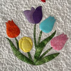 a quilted wall hanging with colorful flowers on it