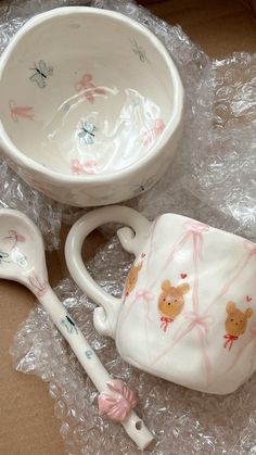 a bowl, spoon and cup sitting on plastic wrap