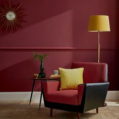 a living room with red walls and yellow pillows on the chair next to the coffee table