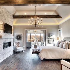 a large bedroom with wood floors and a fireplace in the corner, along with a bed that has pillows on it