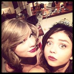 two young women wearing tiaras and posing for the camera in front of a kitchen counter