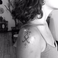 a woman with a cross tattoo on her upper arm and shoulder, in black and white